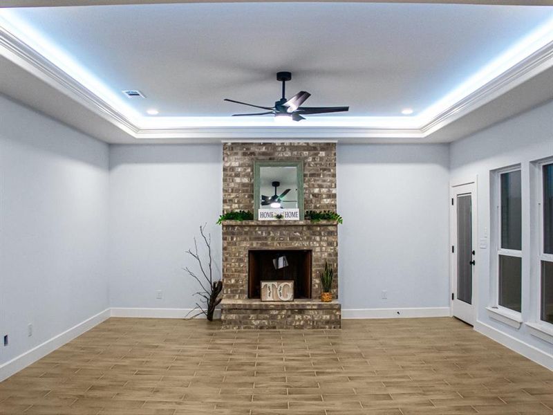 Unfurnished living room with ceiling fan, recessed lighting, a tray ceiling, wood finished floors, and ornamental molding