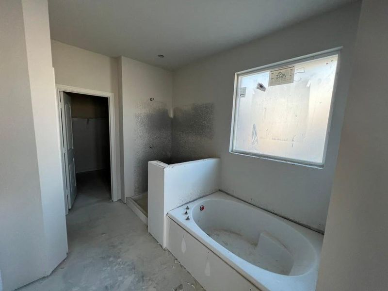 Full bath featuring a bath, a spacious closet, and a stall shower