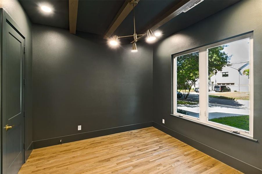 Interior space featuring wood-finish flooring, a large window, a modern ceiling light fixture, exposed ceiling beams, and recessed lighting Interior space featuring wood-finish flooring, a large window, a modern ceiling light fixture, exposed ceiling beams, and recessed lighting