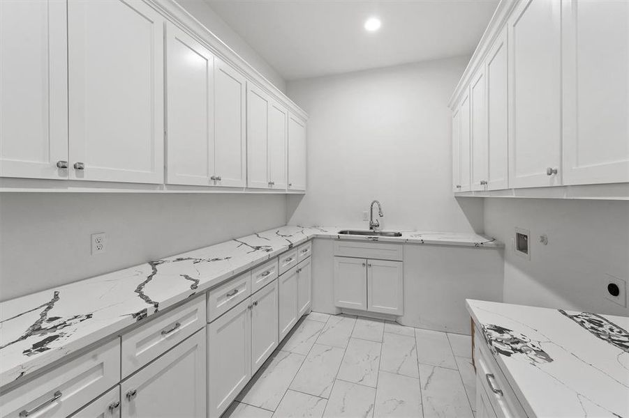 This is a sleek modern kitchen featuring white cabinetry with ample storage and marble-like countertops, complemented by a clean, minimalist design.