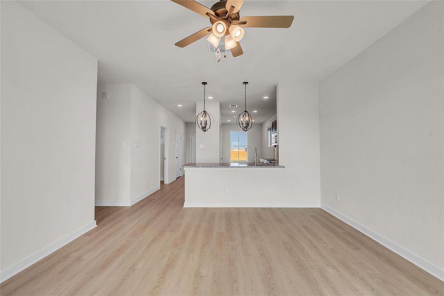 Unfurnished living room featuring recessed lighting, a ceiling fan, light wood-type flooring, and a chandelier
