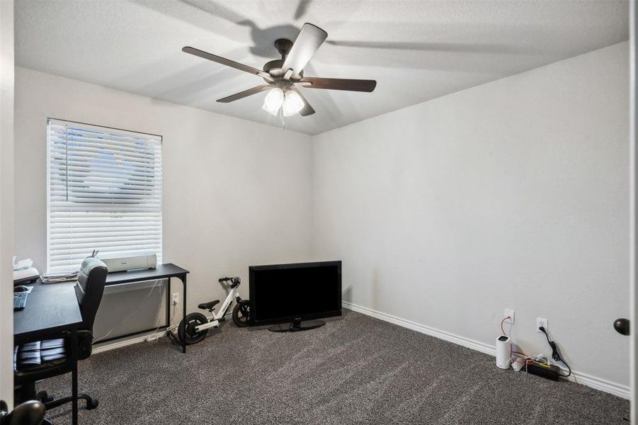 Carpeted office featuring ceiling fan