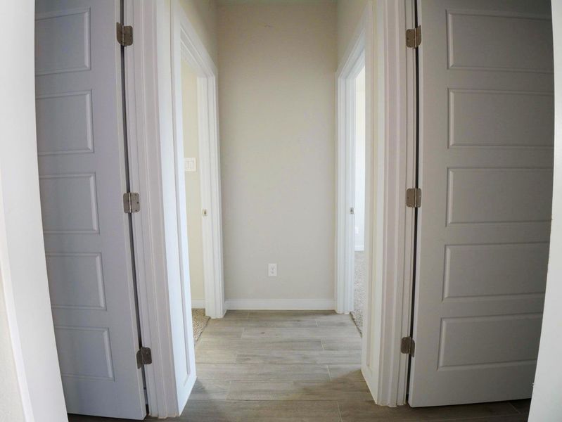 Corridor featuring light wood-style flooring and baseboards Corridor featuring light wood-style flooring and baseboards