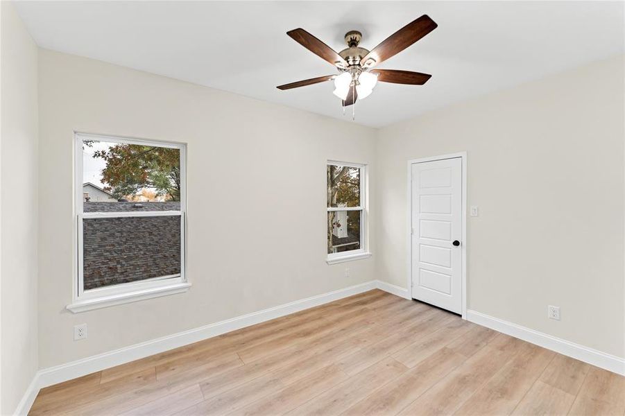 Empty room featuring ceiling fan, plenty of natural light, and light wood-type flooring