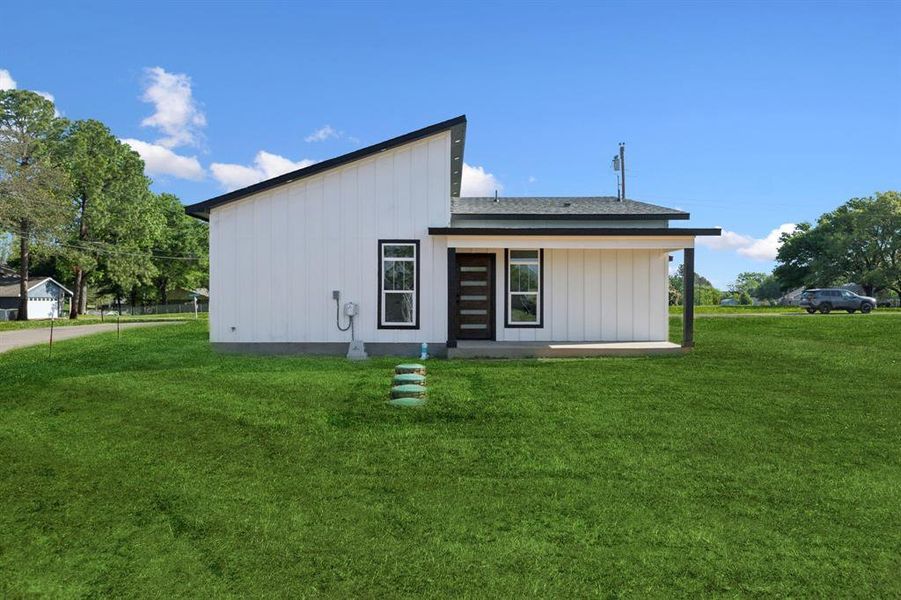 Back of property featuring a yard and board and batten siding Back of property featuring a yard and board and batten siding