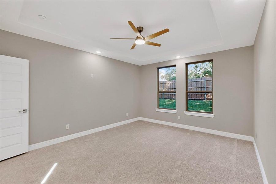 Empty room with light carpet, a tray ceiling, a ceiling fan, and recessed lighting