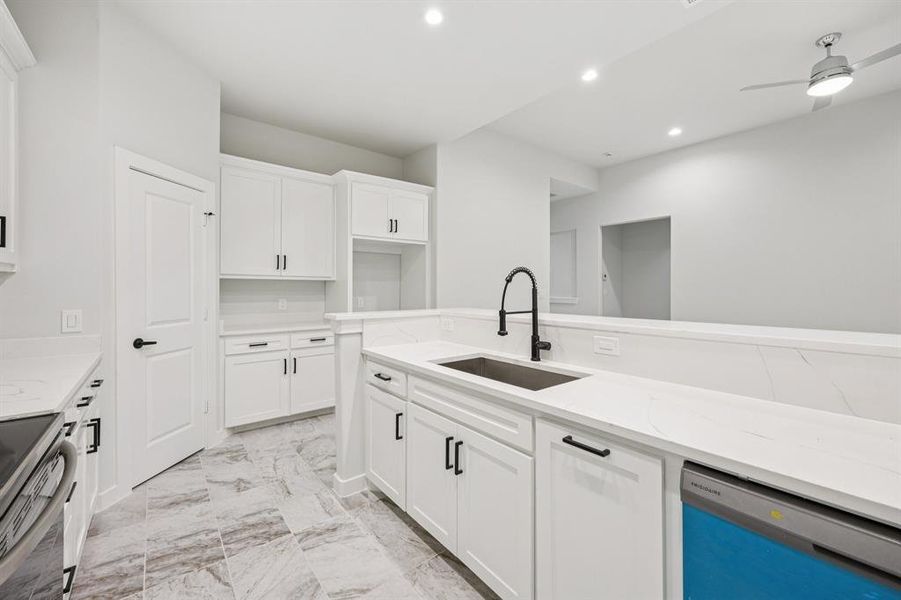 Kitchen with dishwashing machine, recessed lighting, light stone countertops, light marble finish floors, and white cabinetry Kitchen with dishwashing machine, recessed lighting, light stone countertops, light marble finish floors, and white cabinetry
