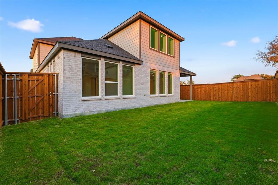 Back of property with brick siding, a gate, roof with shingles, and a fenced backyard