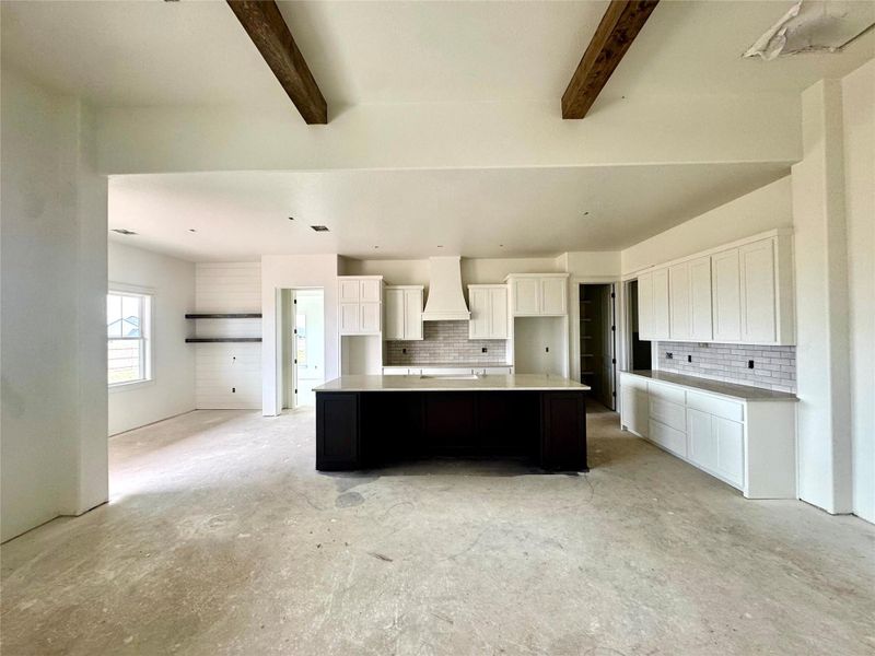 An open-concept living space highlights a large kitchen island and exposed ceiling beams, ready for personalization.