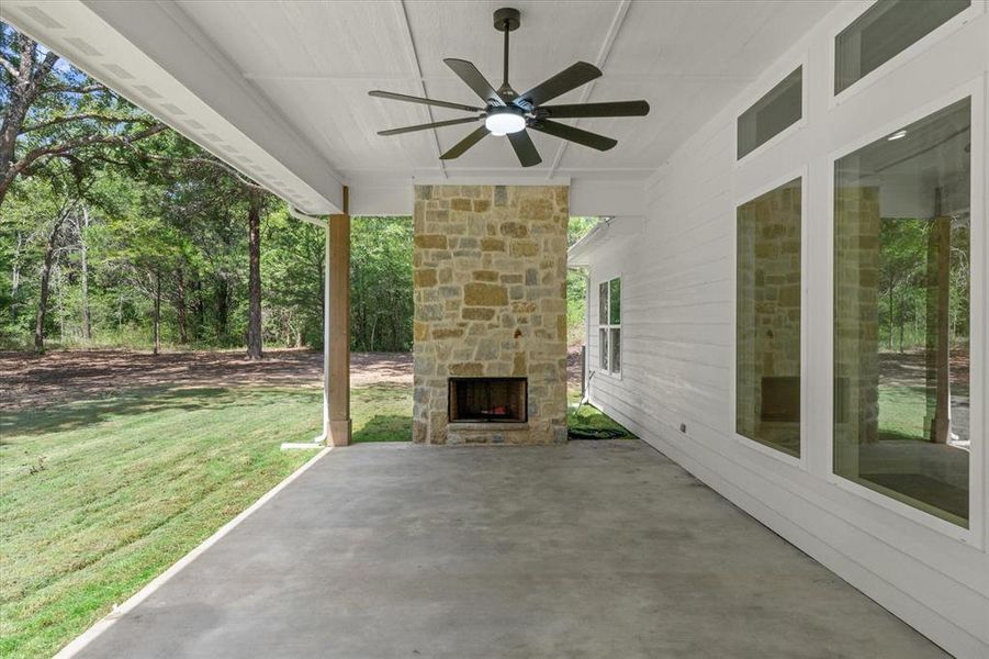 View of patio featuring an outdoor stone fireplace and a ceiling fan View of patio featuring an outdoor stone fireplace and a ceiling fan