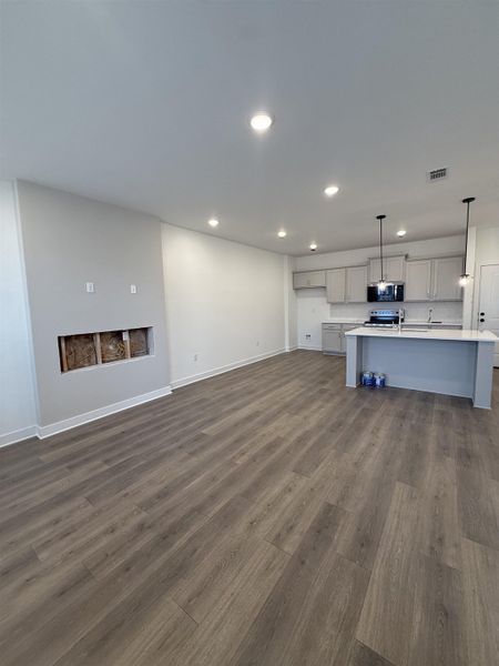 Unfurnished living room with dark wood-type flooring and recessed lighting