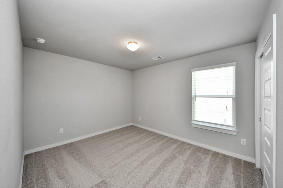 Secondary bedroom features plush carpeting, large windows that let in plenty of natural light, bright paint, and spacious closets. Sample photo of completed home with similar floor plan. Actual colors and selections may vary. Secondary bedroom features plush carpeting, large windows that let in plenty of natural light, bright paint, and spacious closets. Sample photo of completed home with similar floor plan. Actual colors and selections may vary.