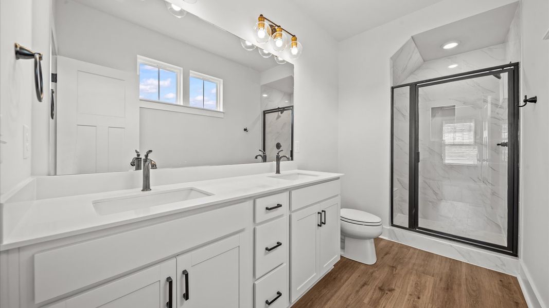 Spacious and modern primary bathroom with tiled walk-in shower and first-class double vanity setup