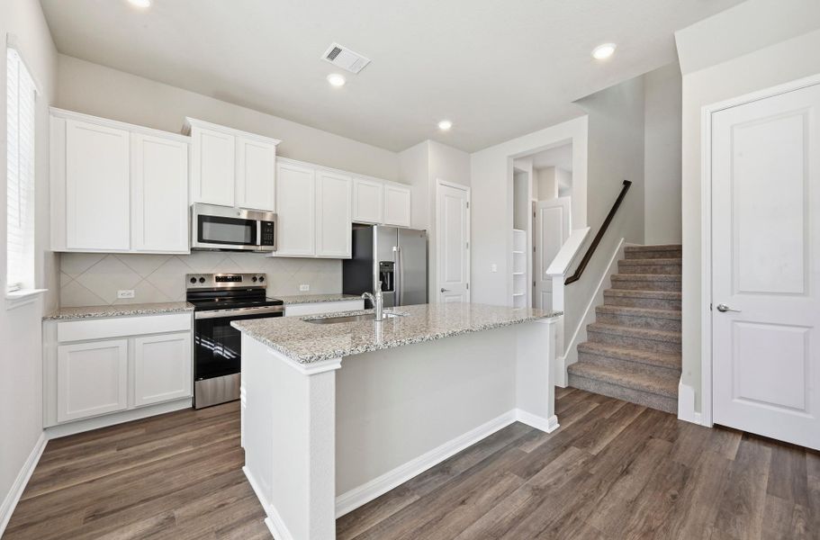 Modern kitchen featuring white cabinetry, stainless steel appliances, granite countertops, and a center island with an undermount sink Modern kitchen featuring white cabinetry, stainless steel appliances, granite countertops, and a center island with an undermount sink