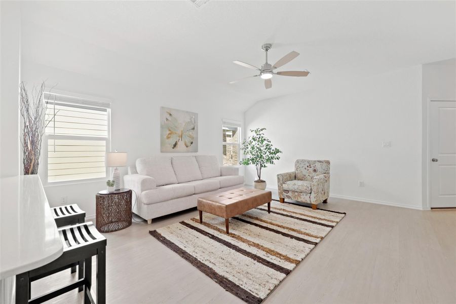 Soaring vaulted ceilings and a modern fan crown this expansive living space, featuring a clever layout designed to maximize every square foot for versatile seating