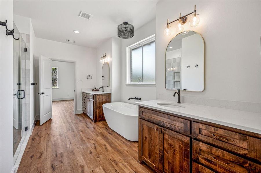 Bathroom featuring independent shower and bath, dual vanity, and wood-type flooring