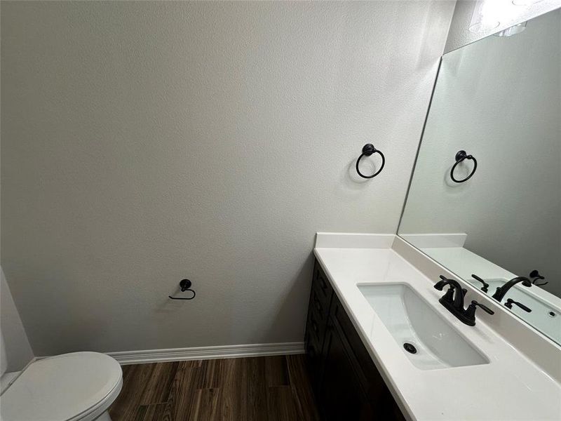 Half bathroom featuring vanity and dark wood-style floors Half bathroom featuring vanity and dark wood-style floors