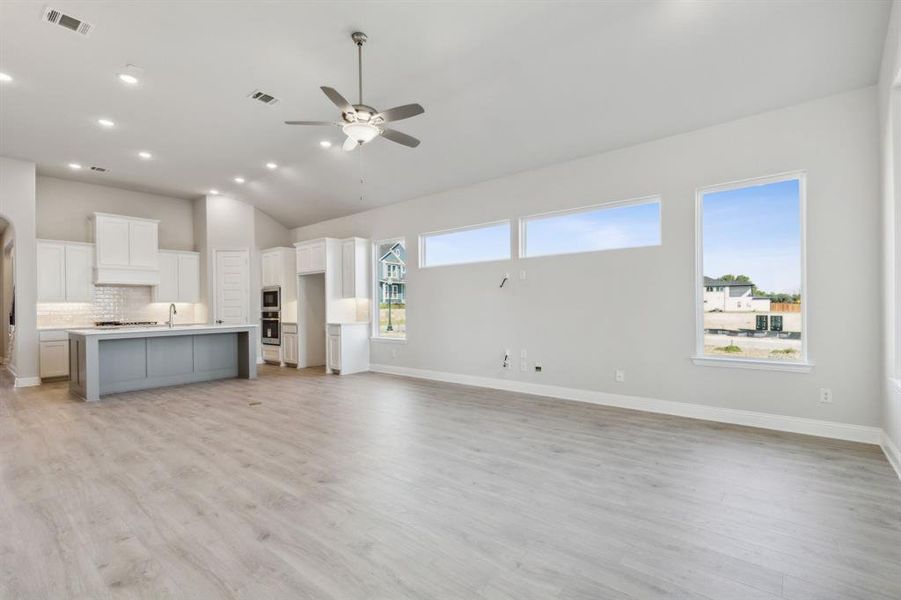 Unfurnished living room featuring a healthy amount of sunlight, light wood-type flooring, and vaulted ceiling