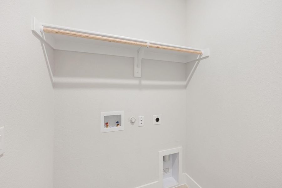 Laundry room with wall-mounted shelf, clothes rod, washer hookups, and dryer outlet connections