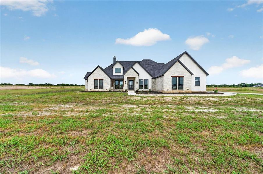 Modern farmhouse exterior with light-colored stone and vertical white siding