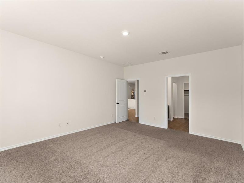 Unfurnished bedroom featuring dark carpet and a walk in closet