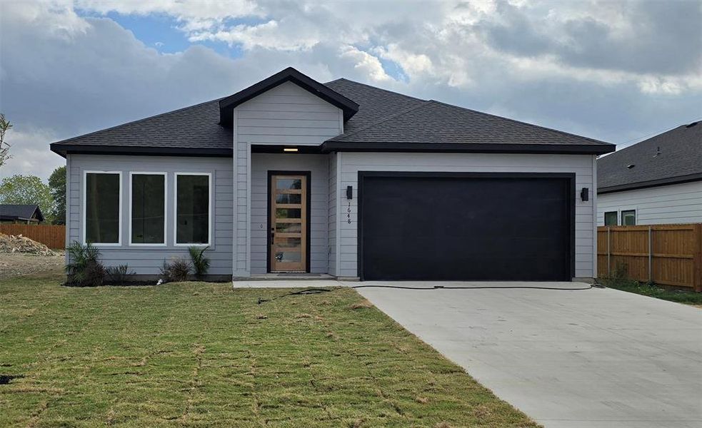 View of front of home featuring a front yard and a garage