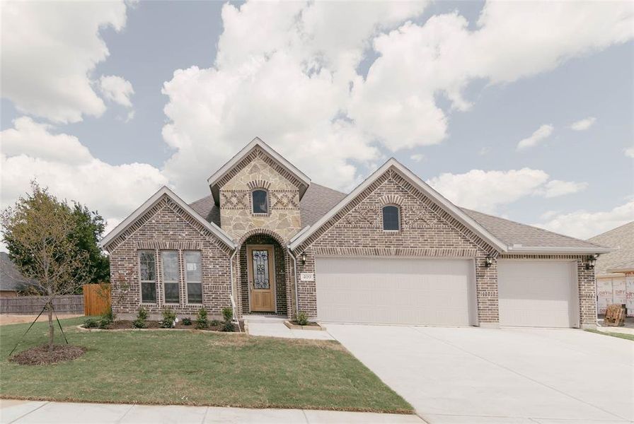 View of front of property featuring a garage and a front lawn