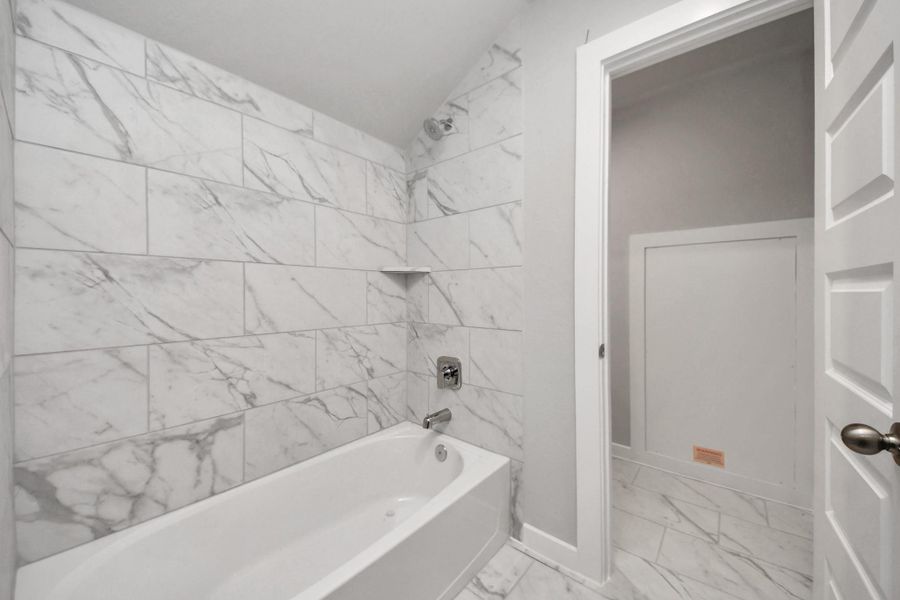 Experience convenience in the secondary bathroom, designed for Jack and Jillarrangements, now with a separate vanity area. This well-appointed spaceshowcases stylish tile flooring, a bath/shower combo with an elegant tilesurround, and light-stained wood cabinets. The beautiful light countertop adds atouch of sophistication, combining functionality and aesthetics seamlessly.