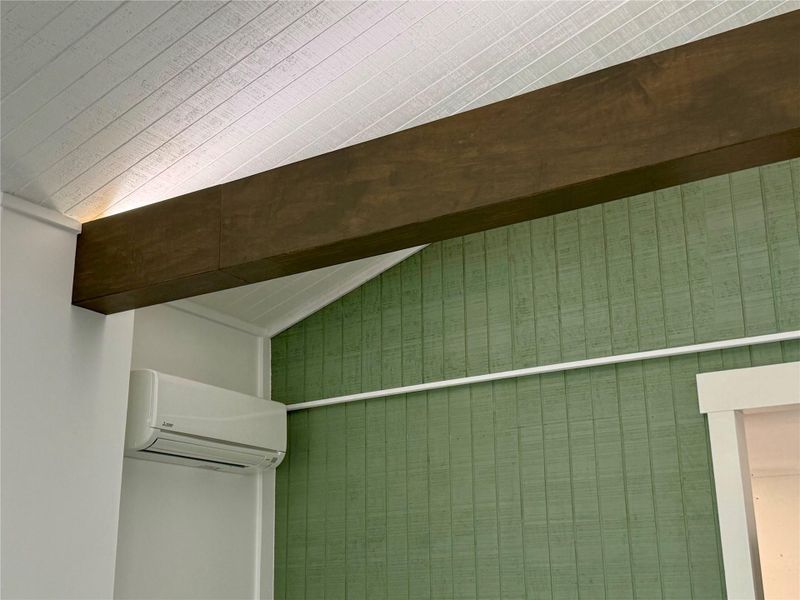 Mini Split Ductless AC unit. Varying textures of wood paneling and exposed beams create architectural interest in this room.