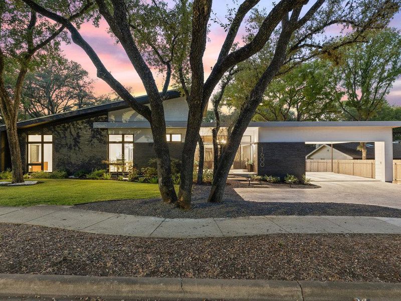 Mid-century modern home featuring a yard, brick siding, and concrete driveway