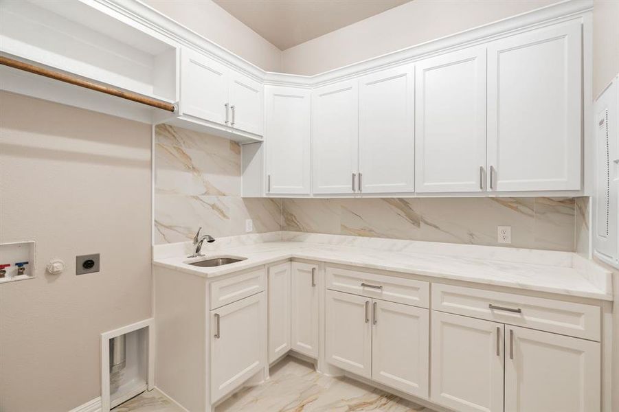 Clothes washing area with electric dryer hookup, cabinets, washer hookup, and sink