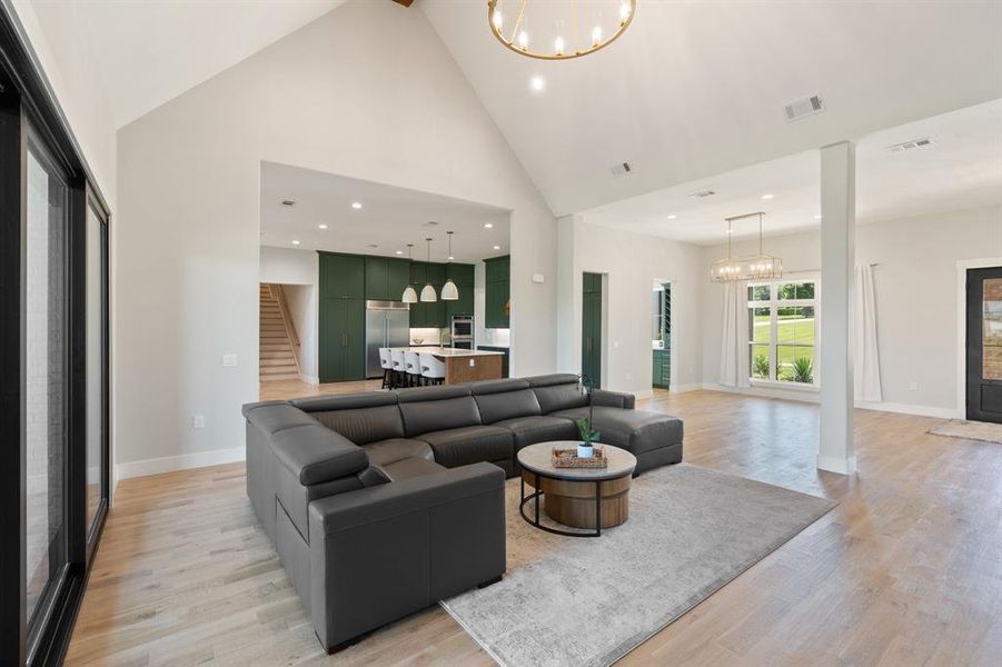 Living room with high vaulted ceiling, an inviting chandelier, and light hardwood / wood-style flooring