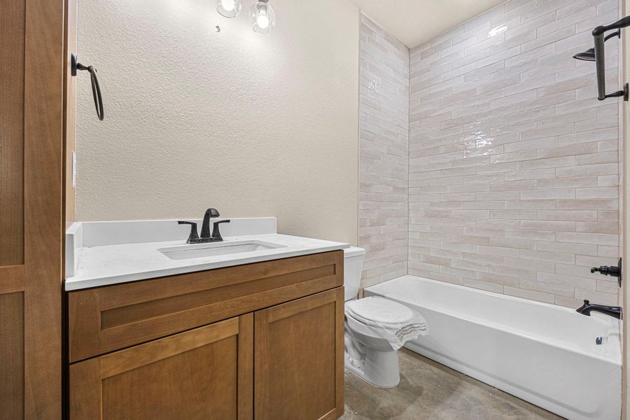 Bathroom with vanity, a textured wall, and bathtub / shower combination