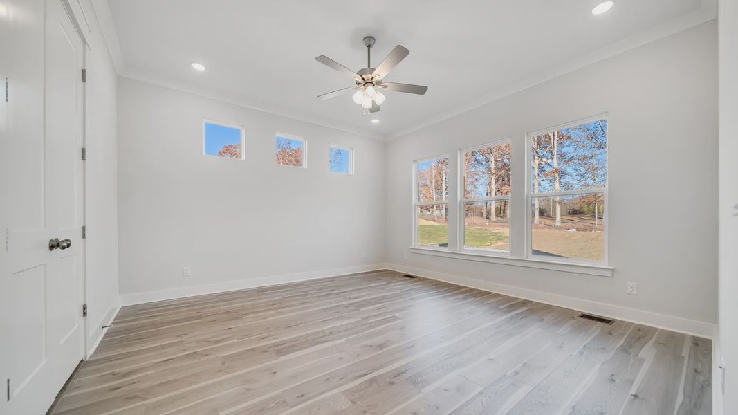 Large bedroom with hard-surface flooring, 6 windows, and ceiling fan