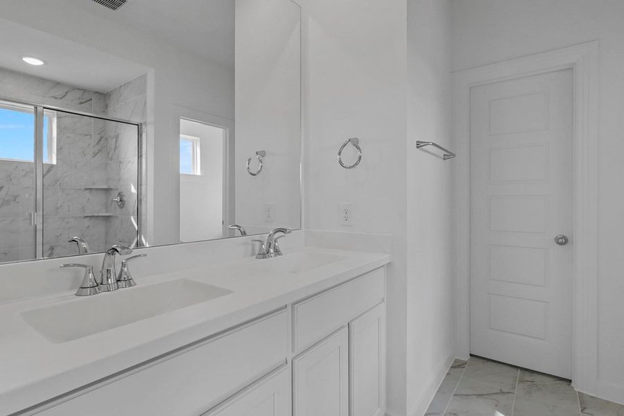 The primary bathroom features double sinks and a large mirror, creating a spacious and functional setting for daily routines.