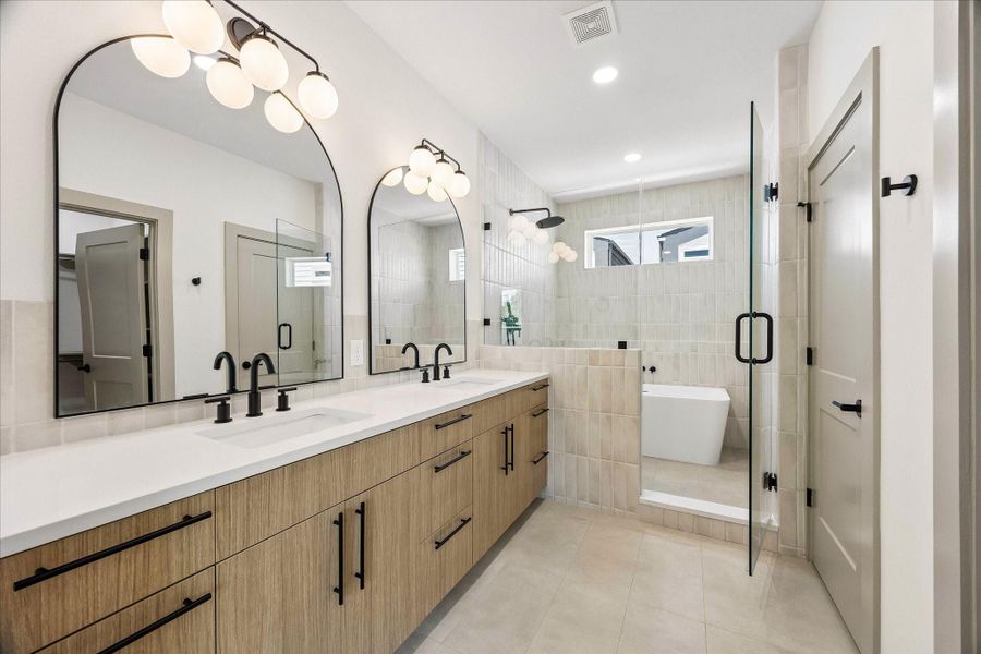 Dual quartz vanities, warm wood cabinetry, oversized arched mirrors, and matte black fixtures bring together modern functionality and timeless design.