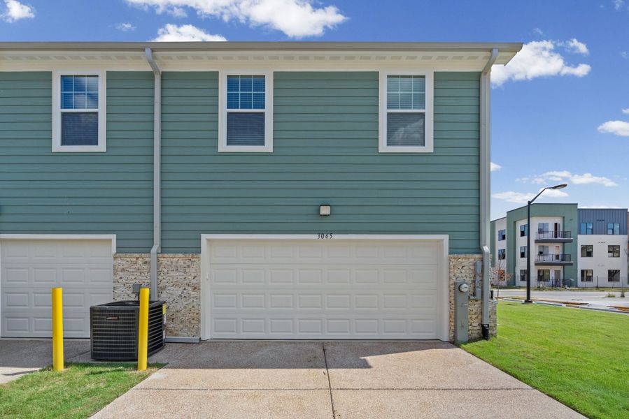 Teal siding exterior with white trim windows and a white paneled garage door