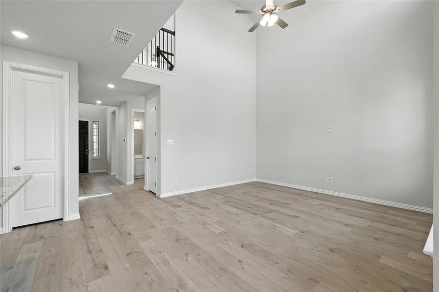 Unfurnished dining area featuring a towering ceiling, light wood-type flooring, recessed lighting, and a ceiling fan Unfurnished dining area featuring a towering ceiling, light wood-type flooring, recessed lighting, and a ceiling fan