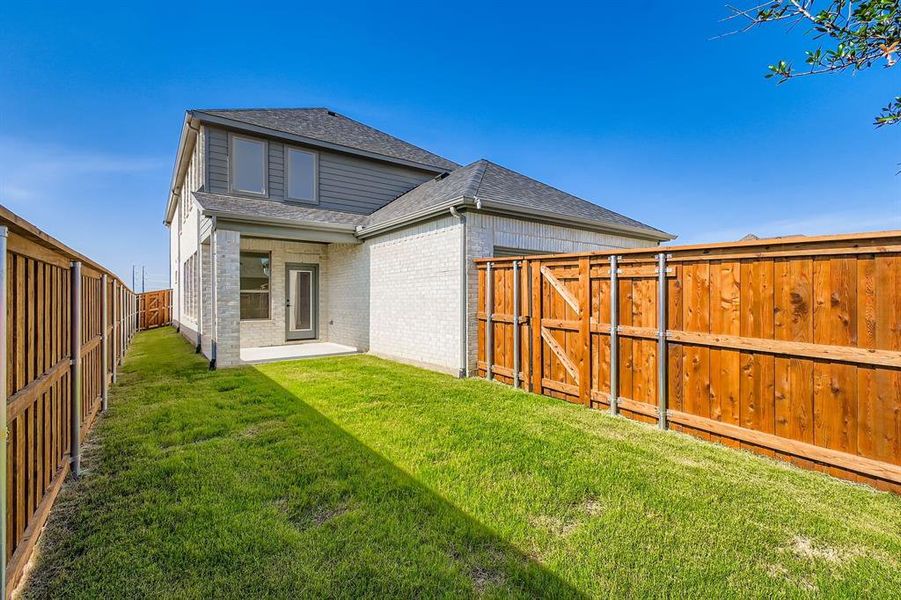 Back of property with roof with shingles, brick siding, a fenced backyard, and a gate