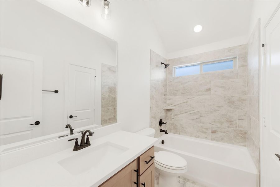 Bathroom with single vanity, tiled tub-shower combo, and dark bronze fixtures