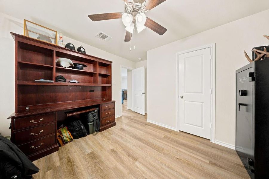 Interior room featuring wood-finish flooring, light-toned walls, and a ceiling fan with integrated lighting Interior room featuring wood-finish flooring, light-toned walls, and a ceiling fan with integrated lighting