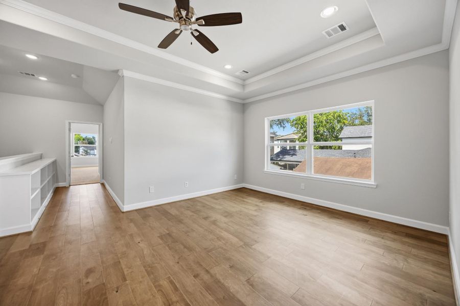 Let the fun begin in this vibrant game room, with a tray ceiling, ceiling fan, and a wall of windows flooding the space with light.