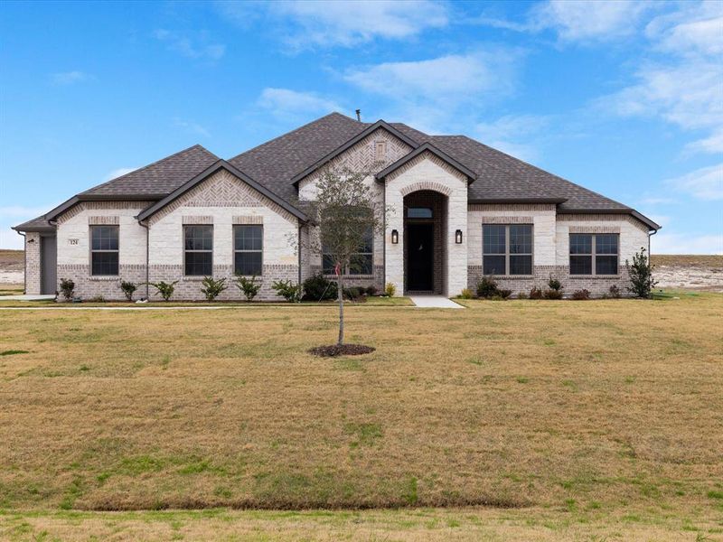 French country style house featuring brick siding, a front lawn, and roof with shingles