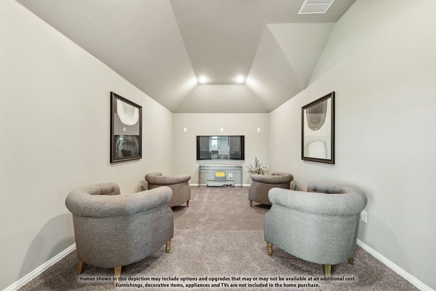 Media room with vaulted ceiling, four gray chairs, wall-mounted TV, and carpet flooring