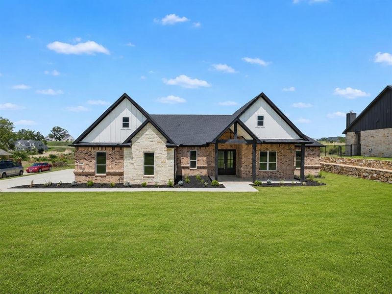 Contemporary home featuring a brick and stone exterior with board-and-batten gables