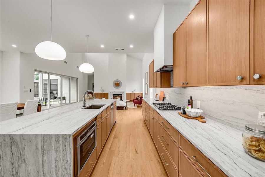 Gourmet kitchen featuring a large island with integrated sink, wood-finish cabinetry, stainless steel appliances, and light-toned countertops