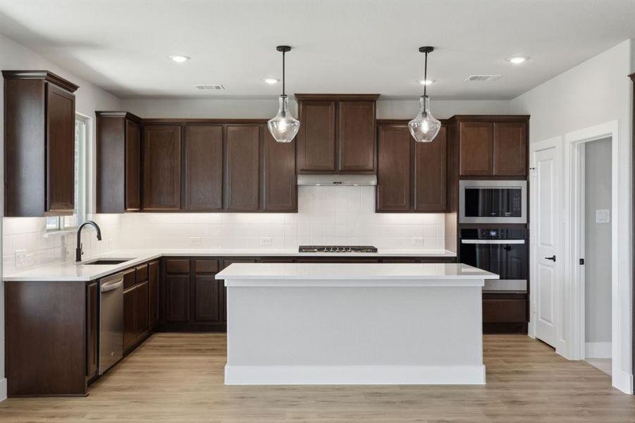 Kitchen featuring visible vents, under cabinet range hood, stainless steel appliances, dark brown cabinetry, and light countertops