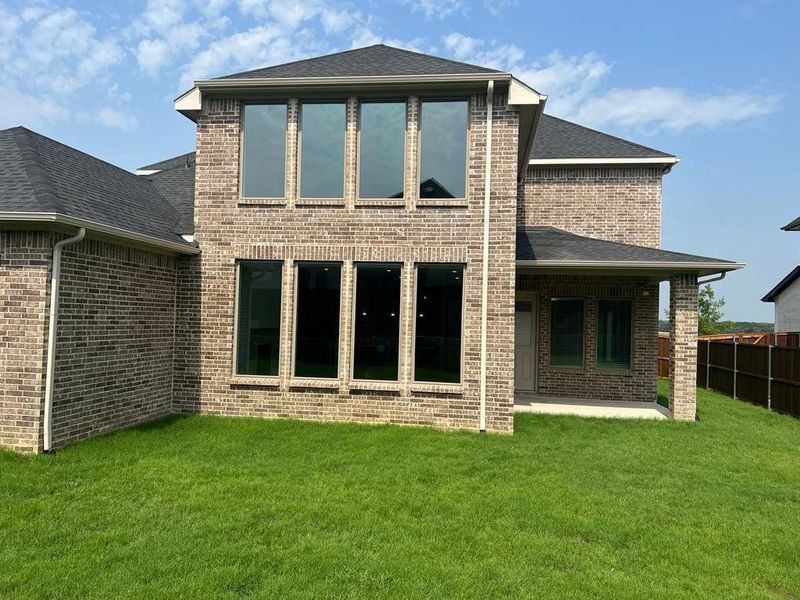 Rear view of property featuring a patio area, brick siding, and a shingled roof