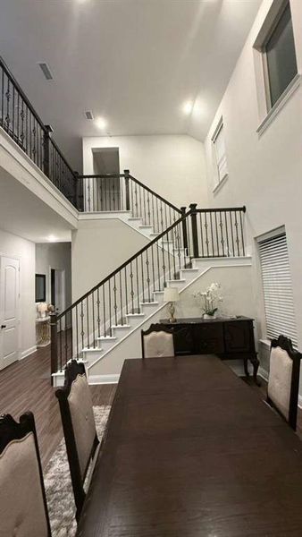 Dining area featuring stairs, a towering ceiling, and dark wood finished floors