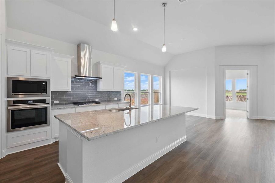 Kitchen featuring a sink, wall chimney range hood, stainless steel appliances, and plenty of natural light
